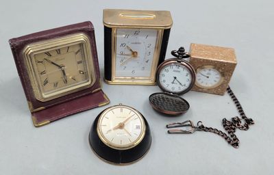 trois horloges et une montre de poche posées sur une table