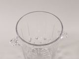 a clear glass vase with a handle on a white surface