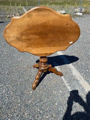 a small wooden table on a tripod with a shadow on the ground