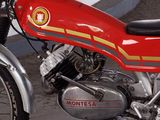 a red motorcycle parked next to a white wall