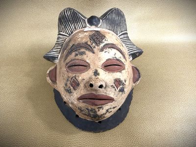 a mask with a bow on it on the wall
