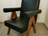 un fauteuil en cuir noir avec des pieds en bois dans une pièce