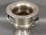 an image of a silver cup with handles on a gray surface