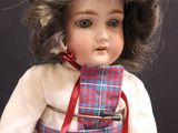 a doll that is wearing a white dress and a red bow