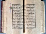 an open book with arabic writing sitting on top of a table