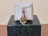 a small white box with a gold tear charm on top of it