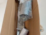 une cuvette de WC blanche dans un carton, avec une brosse à l'intérieur