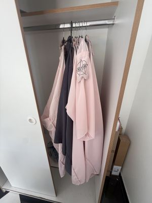 une armoire avec des vêtements suspendus à l'intérieur, dans un coin de la pièce
