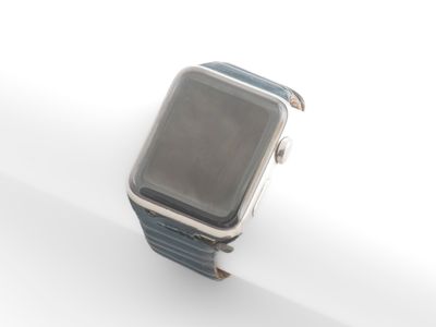 une Apple Watch argentée posée sur une surface blanche