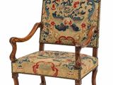 une vieille chaise avec un dossier et des accoudoirs tapissés de fleurs