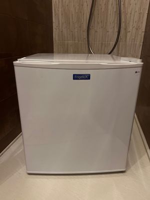 un petit réfrigérateur blanc posé sur un plan de travail dans une salle de bains