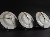 three plates with a clock on them sitting on a table