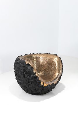 un bol noir et doré posé sur une surface blanche