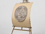un chevalet sur lequel sont posés un tableau et une pièce de monnaie
