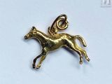 a close up of a gold horse charm on a white surface
