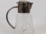 an antique silver plated glass pitcher with a silver lid and handle