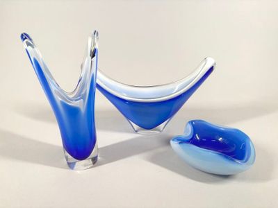 deux vases en verre bleu posés l'un à côté de l'autre sur une surface blanche