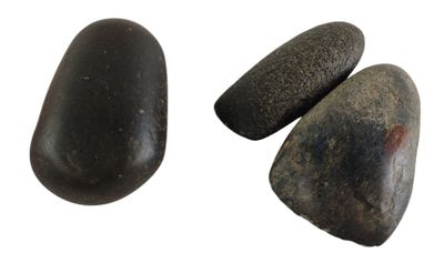 three black rocks sitting next to each other on a white surface