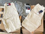 trois paires de pantalons pour homme posées sur des cartons dans un entrepôt
