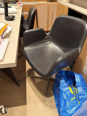 a black chair sitting in front of a desk with a blue bag on it