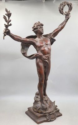 une statue antique en bronze représentant une femme tenant une couronne et un oiseau