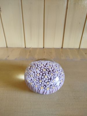 un presse-papier orné de fleurs violettes et blanches, posé sur une table en bois