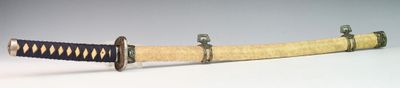 un gros plan d'un sabre de samouraï posé sur une surface blanche