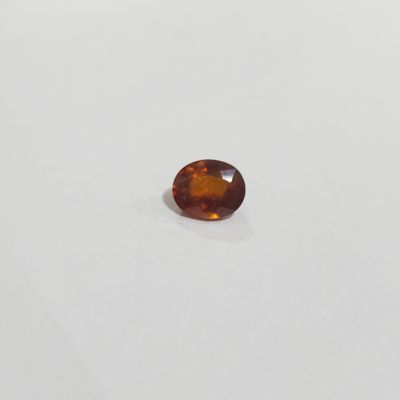 un gros plan d'un saphir orange de forme ovale posé sur une surface blanche