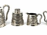 five silver teapots and a coffee pot on a white surface