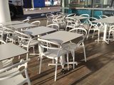 tables and chairs in front of a building with a truck in the background