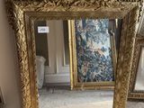 un grand miroir posé par terre à côté d'un vase