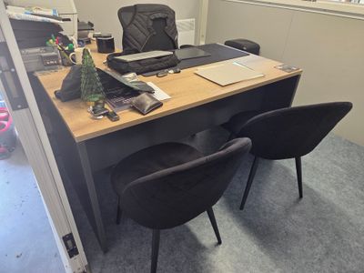 a desk with two chairs and a laptop on it