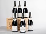 six bouteilles de vin rouge sont posées devant une caisse en bois