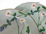 two plates with flowers painted on them sitting on a table