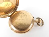 a gold pocket watch sitting on a white surface