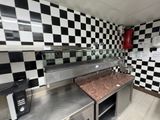une photo d'une cuisine aux murs à carreaux et équipée d'appareils électroménagers en inox