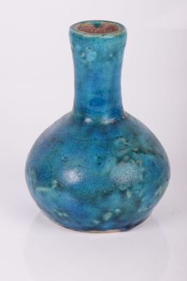 un vase bleu posé sur une surface blanche