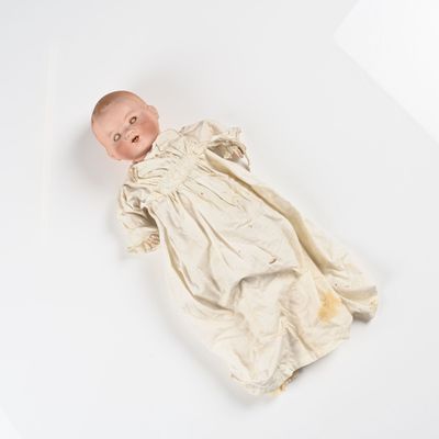 une poupée allongée sur une surface blanche