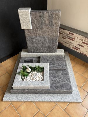 une fontaine en pierre avec une plante à l'intérieur, posée sur un sol carrelé
