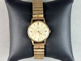 a close up of a gold watch on a black pillow
