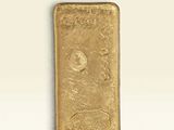 un lingot d'or posé sur une surface blanche, sur fond blanc