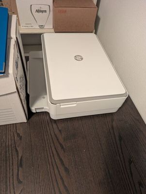 un ordinateur portable blanc posé sur une boîte, à côté d'une imprimante blanche