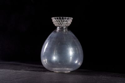 a clear glass vase with a clear top sitting on a black surface