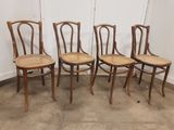 Quatre chaises en bois sont alignées contre un mur dans une pièce