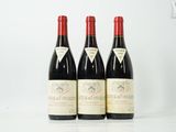 trois bouteilles de vin rouge sont alignées sur une surface blanche