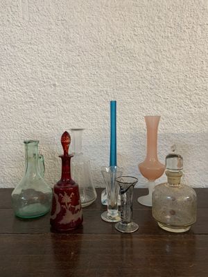 de nombreux vases en verre de différentes formes posés sur une table avec une bougie