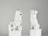 une paire de statues de lions blanches sur des socles, sur fond gris