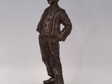 bronze figurine of a boy standing on a rock with his hands on his hips