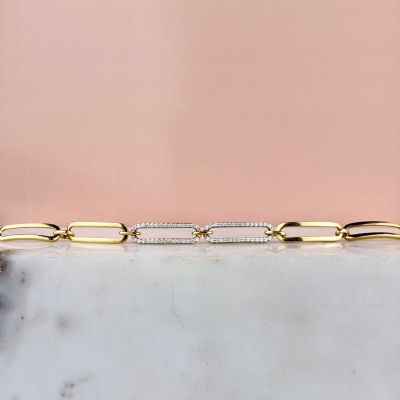 un gros plan d'un bracelet en or et diamants posé sur une surface en marbre