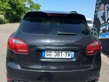 the back of a black car parked in a parking lot next to a building